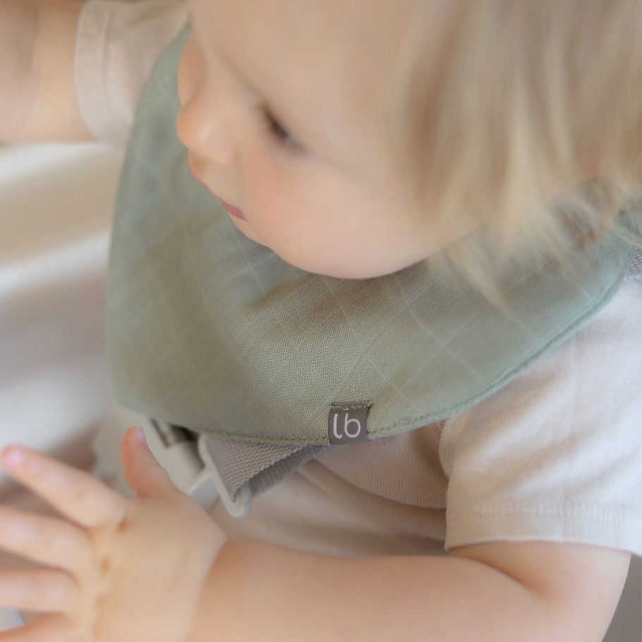 Baby wearing a green bib with a brand logo, close-up shot.