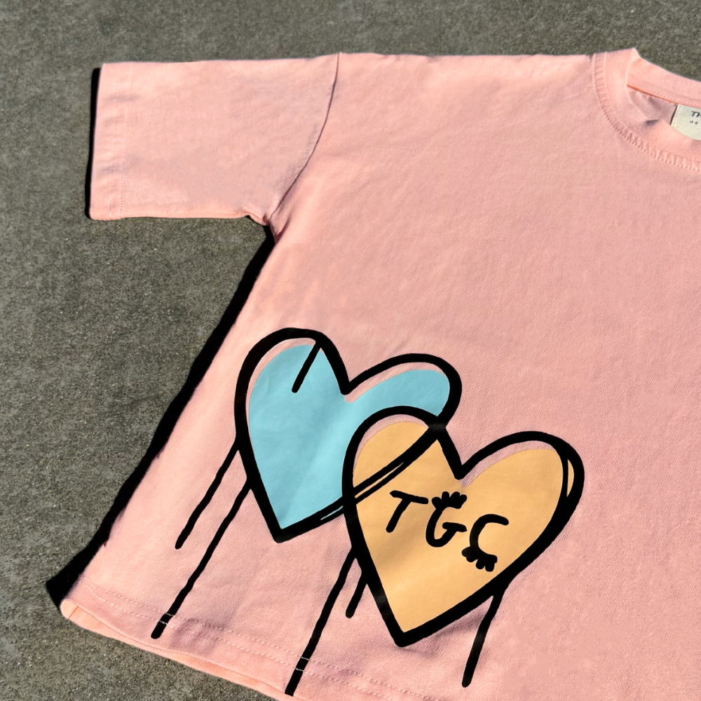 Pink t-shirt with colorful heart design on a gray surface