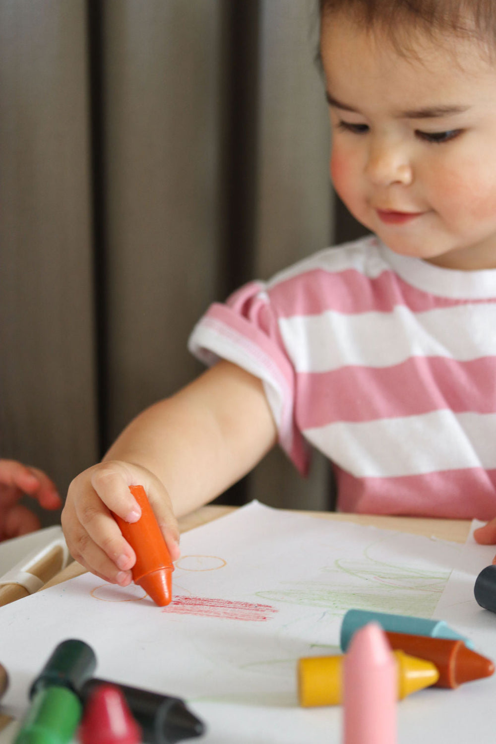 Child drawing with crayons on a piece of paper