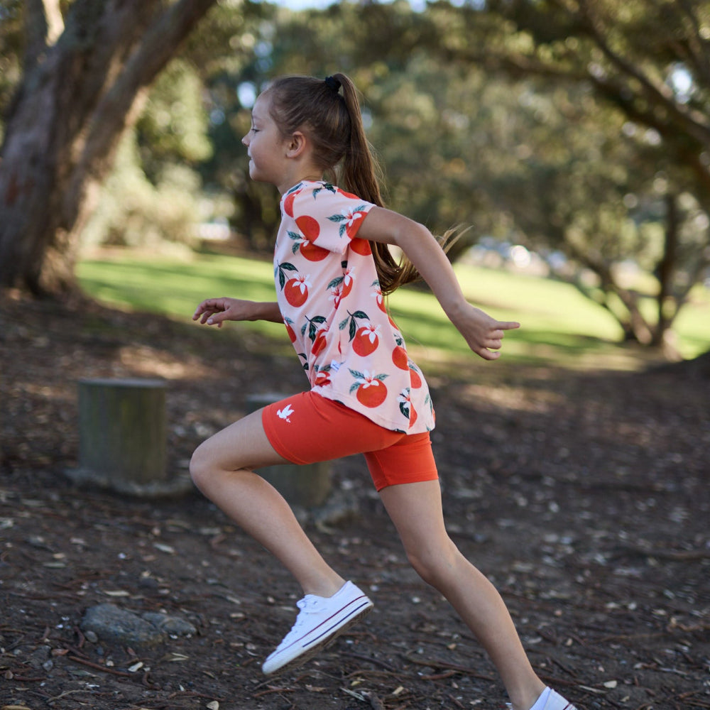 Girl running outdoors in a park with trees and grass in the background