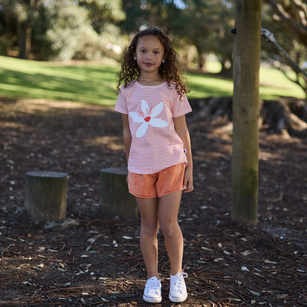 Young girl standing in a park with trees and grass in the background