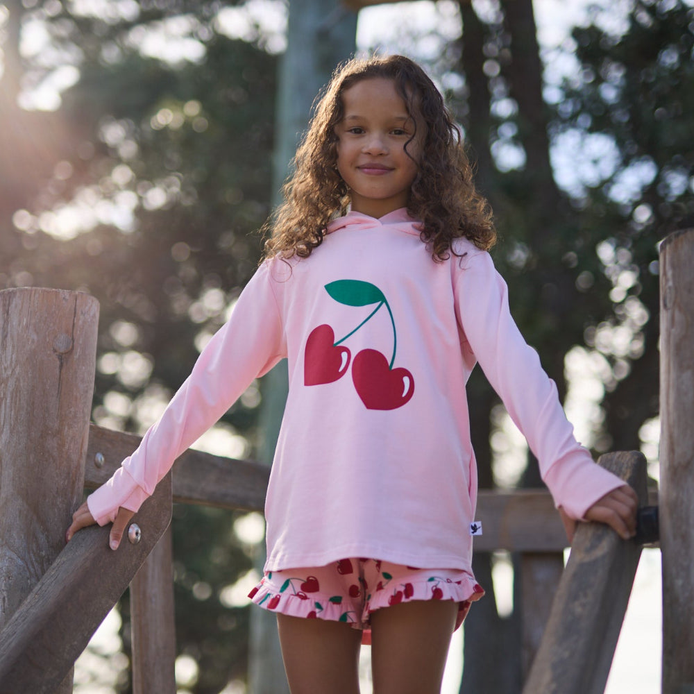 Young girl wearing a pink hoodie with cherry design outdoors