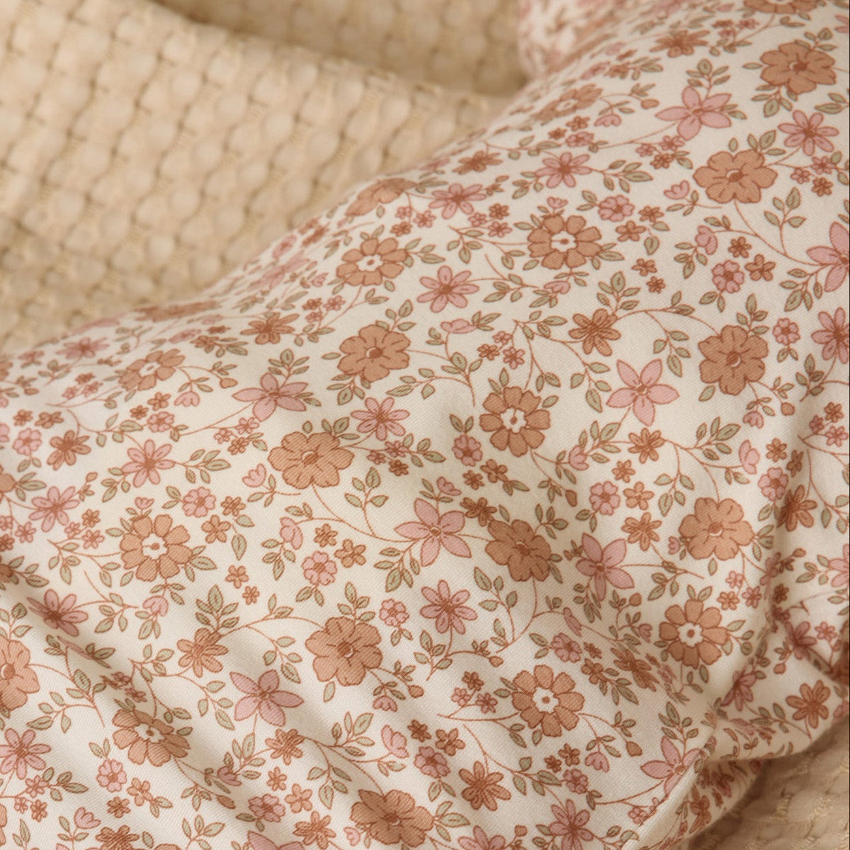 Floral-patterned blanket draped over a wicker basket on a beige surface