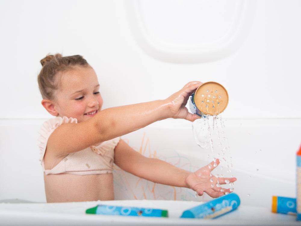 Child playing with a showerhead in a bathtub