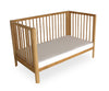 Wooden crib with a white mattress on a white background