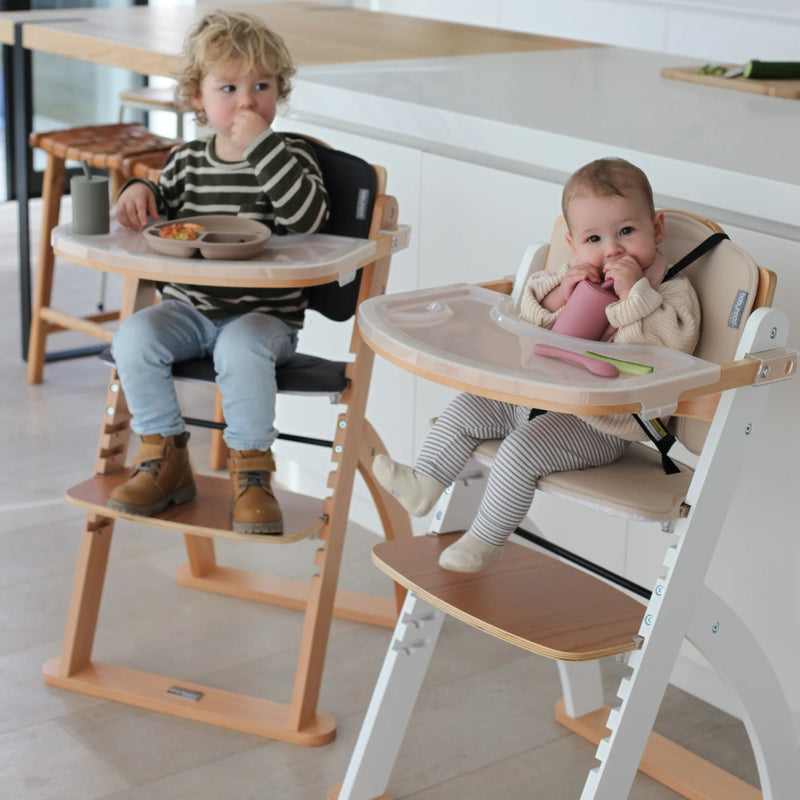Two children sitting in high chairs in a modern kitchen.