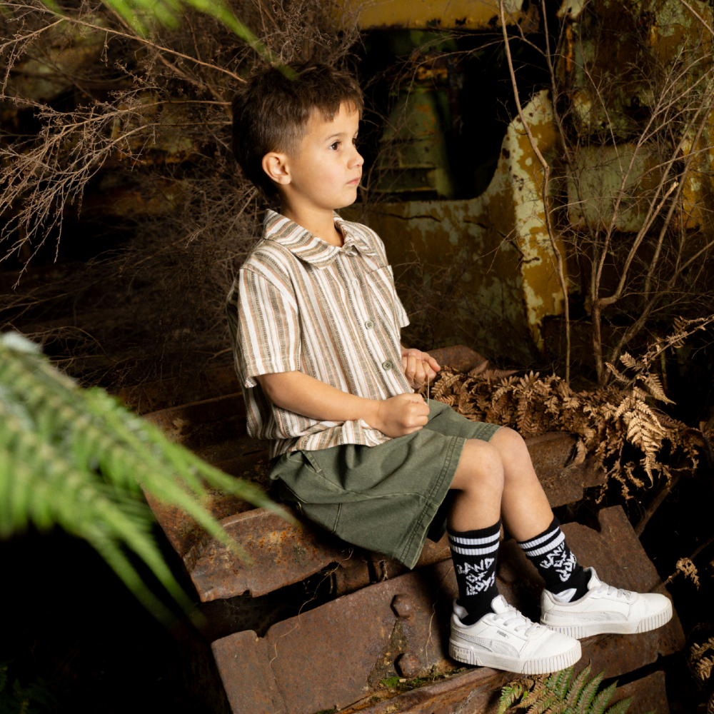 Child sitting on a rusted metal surface with plants around