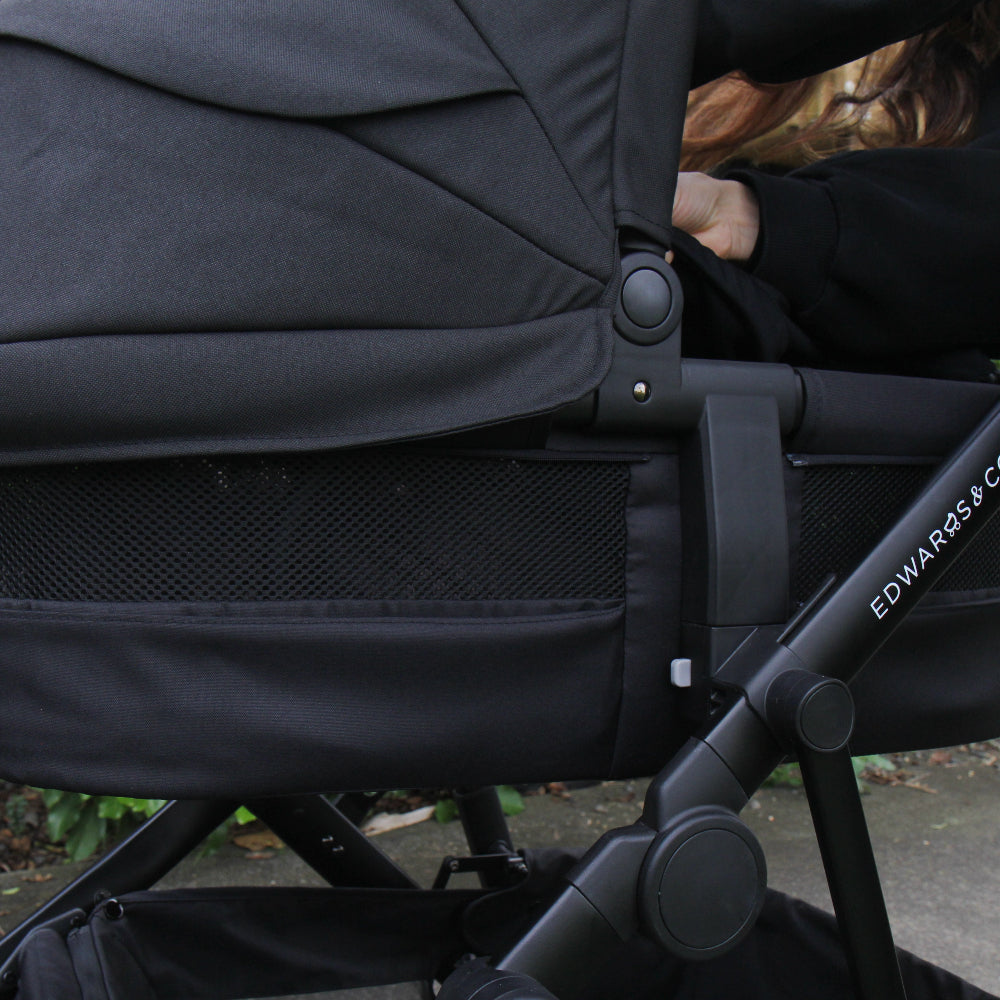Black stroller with a child sitting inside, brand 'Edwards & Co' visible
