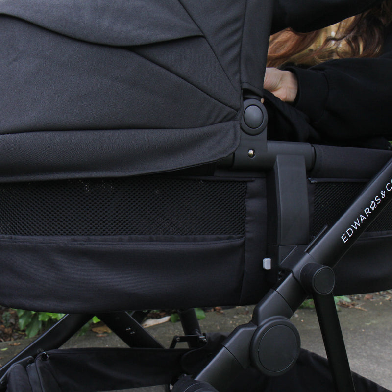 Black stroller with a child sitting inside, brand 'Edwards & Co' visible