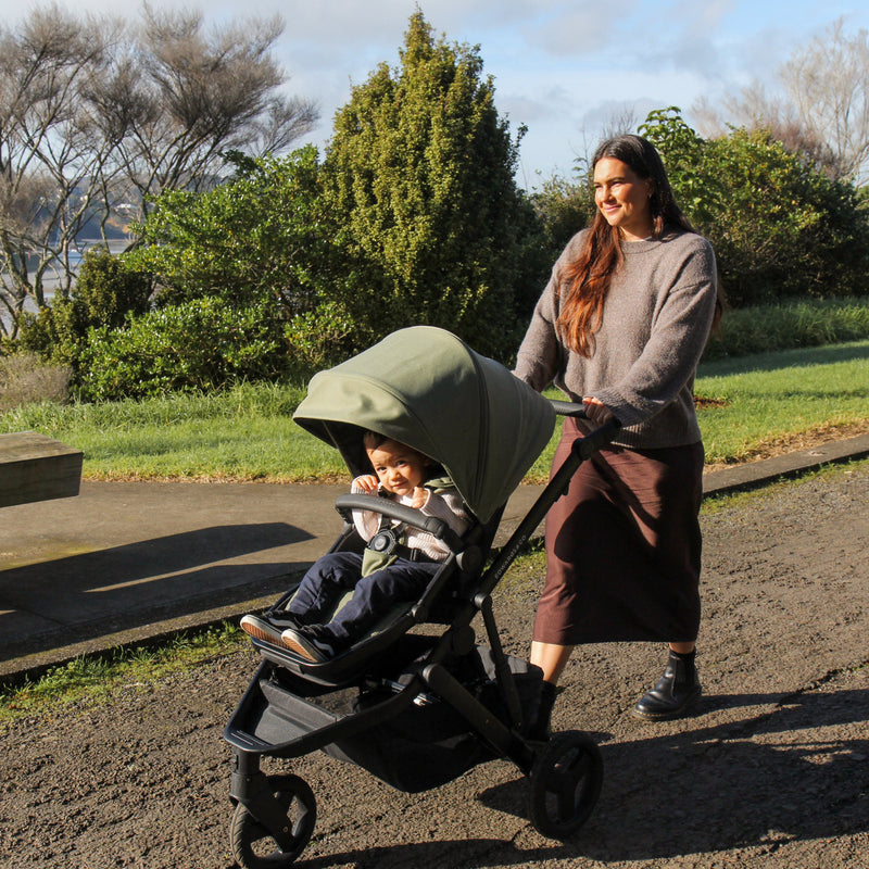 Woman pushing a stroller with a child in a park setting