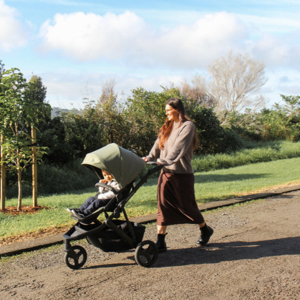 Woman pushing a stroller with a child in a park setting