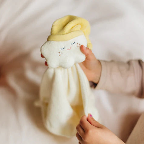 Child holding a soft toy with a neutral expression on a white blanket