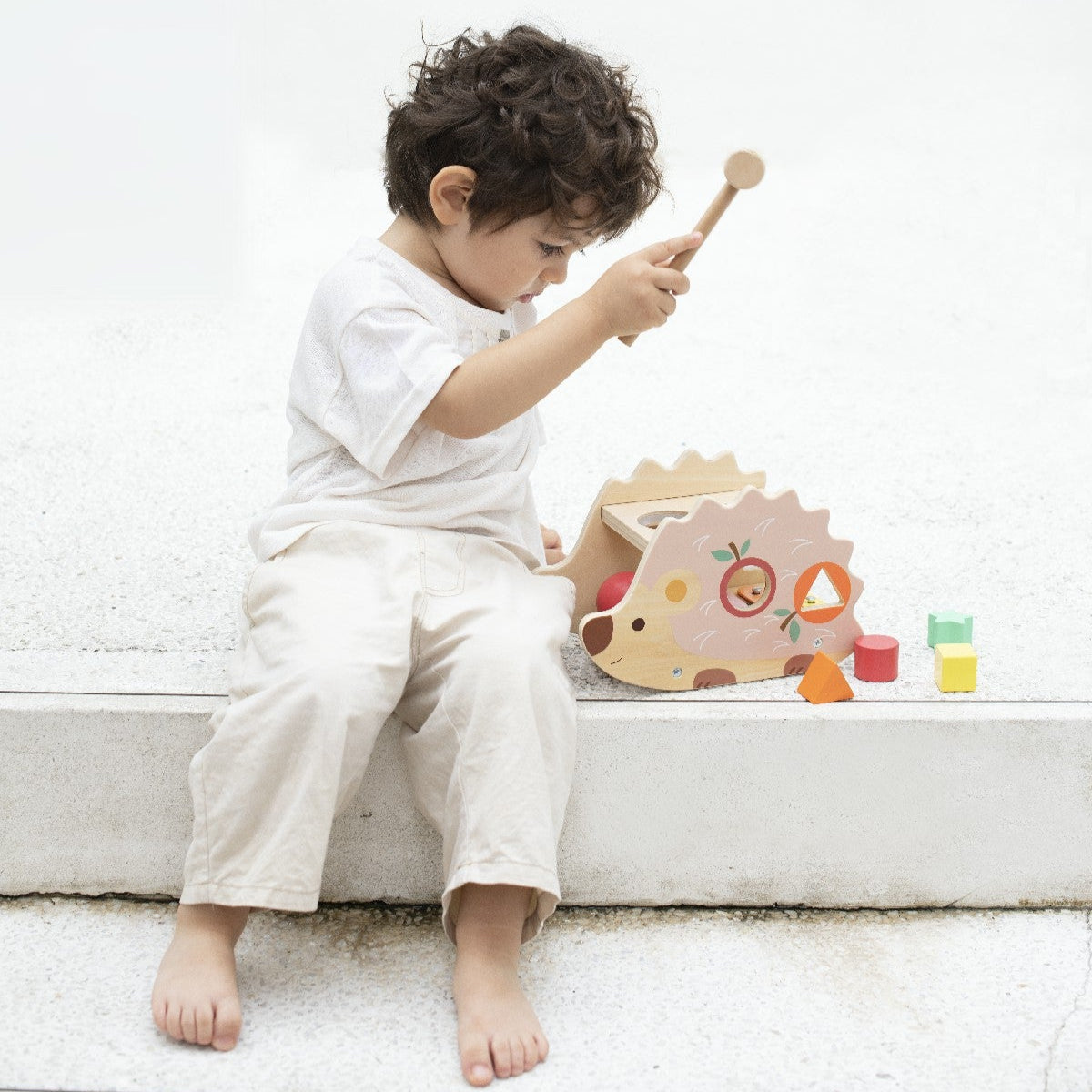 Child playing with wooden toys on a white surface