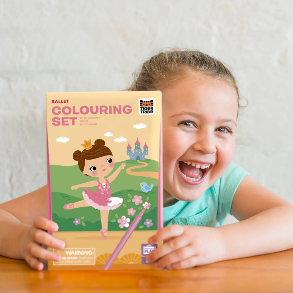 Child holding a 'Ballet Colouring Set' with a smiling expression